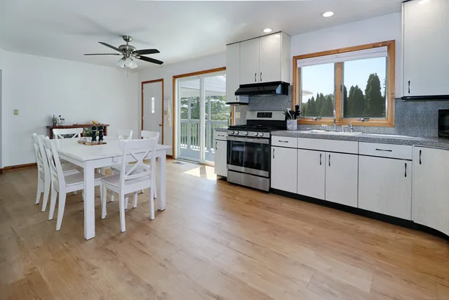 a kitchen with stainless steel appliances a stove a sink and white cabinets with wooden floor