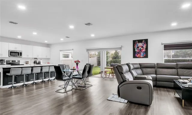 a large room with stainless steel appliances kitchen island granite countertop a sink and a large island with wooden floor