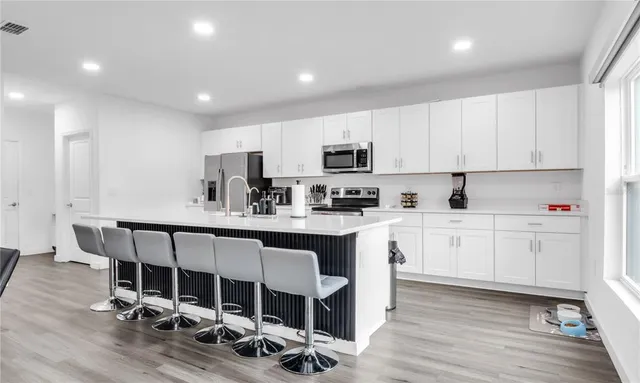 a living room with furniture kitchen view and a wooden floor