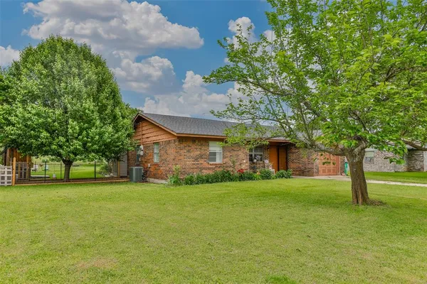 a view of a house with a big yard and large trees