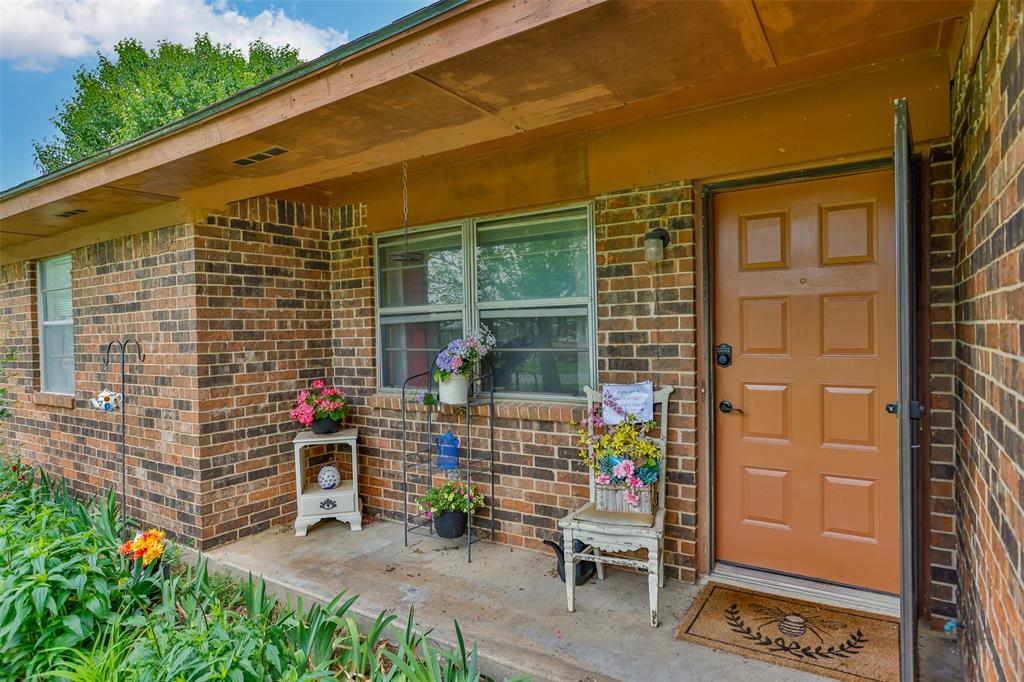 2212 North Aspen Road Gainesville, TX 76240 - Photo 2 of 34 a brick building with a bench and potted plant