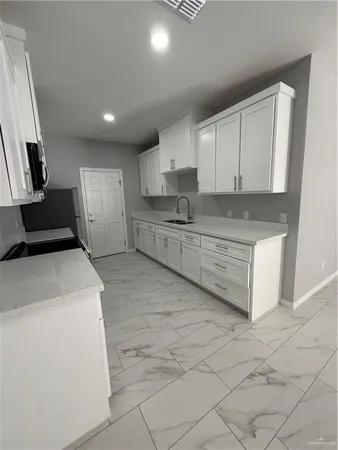 a kitchen with granite countertop a sink a stove top oven and cabinets