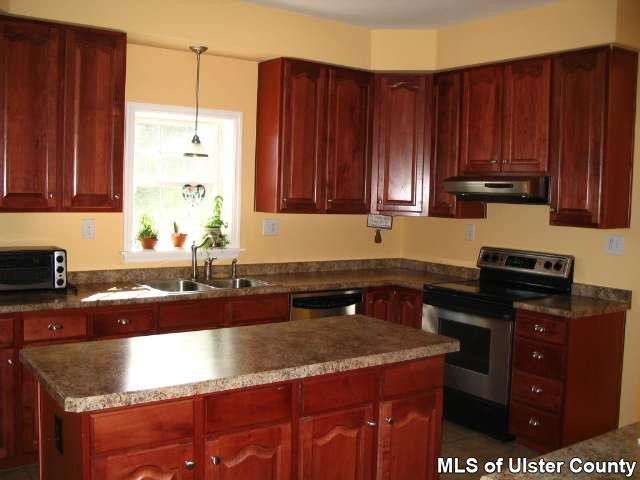 65 Peak Road, Unit HOME WARRANTY IN PLACE Stone Ridge, NY 12484 - Photo 3 of 6 a kitchen with granite countertop a sink a stove and wooden cabinets