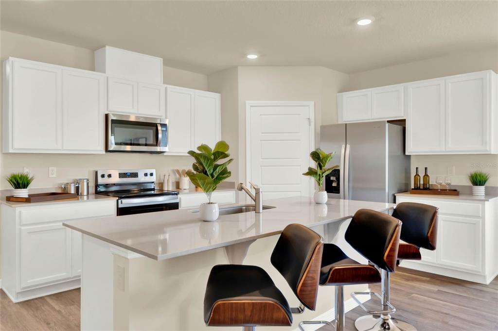 3517 Nettle Loop Tavares, FL 32778 - Photo 11 of 27 a kitchen with stainless steel appliances granite countertop a refrigerator a stove a sink dishwasher a dining table and chairs with wooden floor