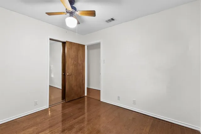an empty room with closet and a ceiling fan