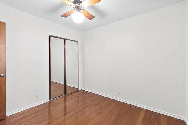 an empty room with wooden floor and fan