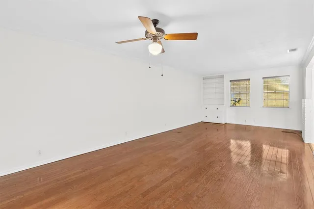 a view of empty room with wooden floor and ceiling fan