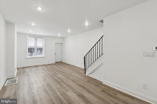a view of an empty room with a window and wooden floor