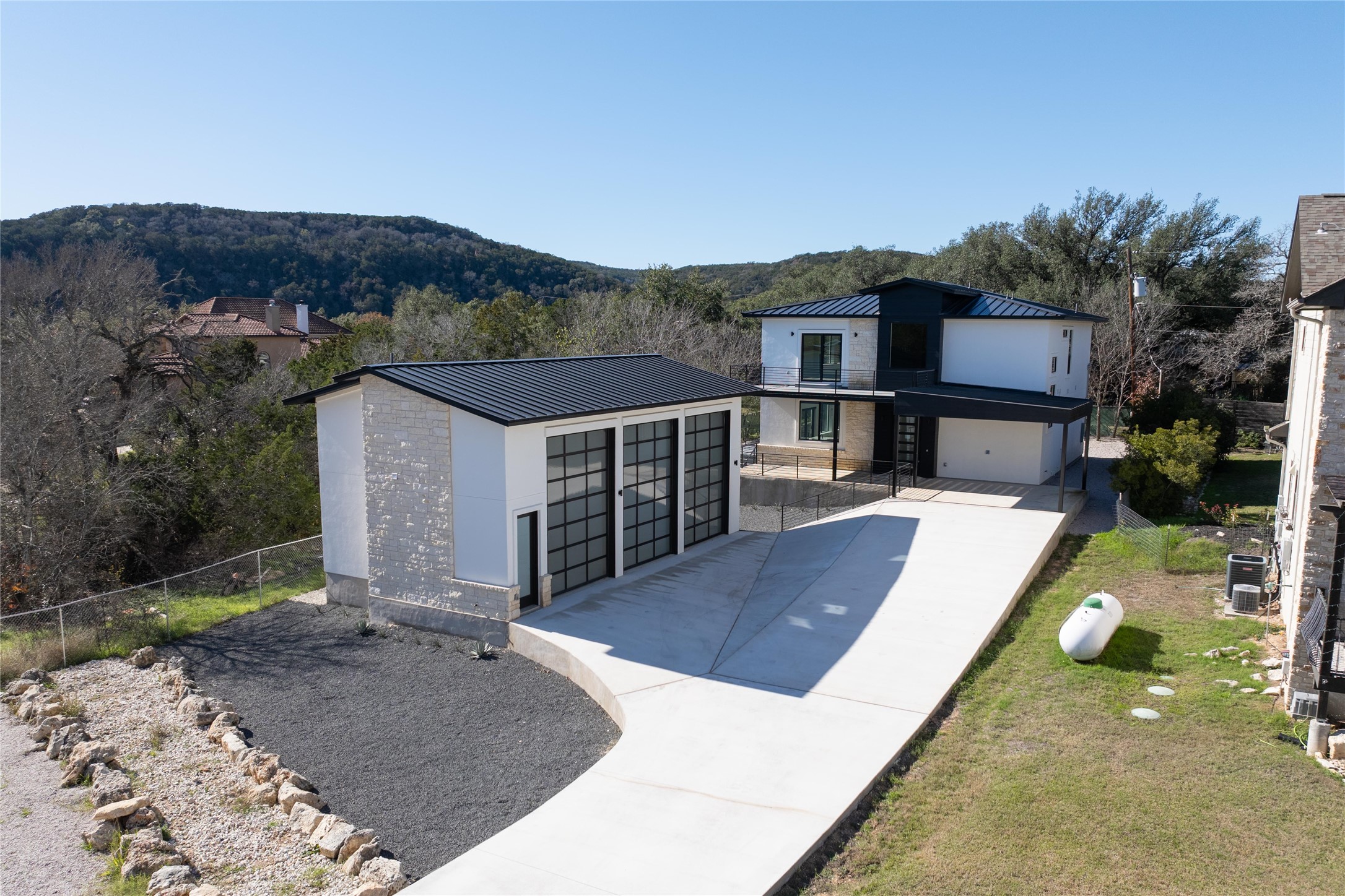 1304 Minnie Drive Austin, TX 78732 - Photo 3 of 28 Contemporary home featuring stone siding, a standing seam roof, stucco siding, and driveway