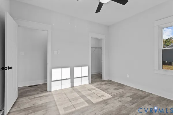 a view of a hallway with wooden floor and a bathroom