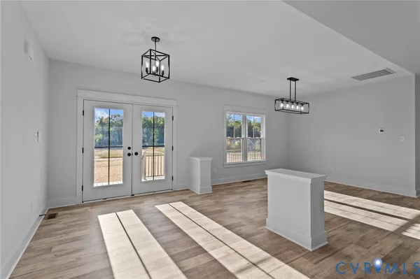 a view of an empty room with window and wooden floor