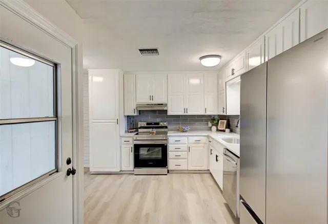 a kitchen with stainless steel appliances granite countertop a stove a sink and a refrigerator