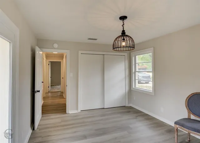 a view of a hallway with wooden floor and a chandelier