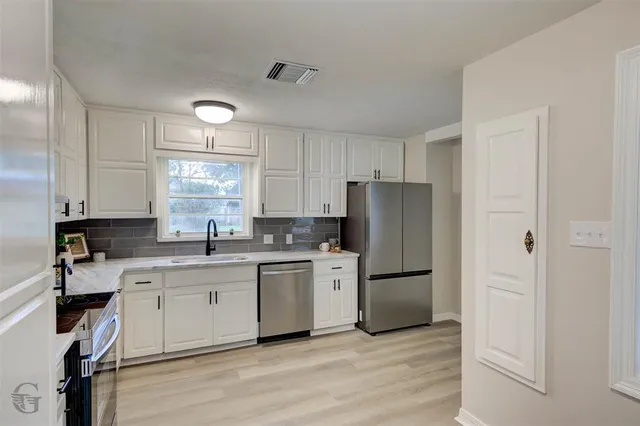 a kitchen with a refrigerator a sink and cabinets