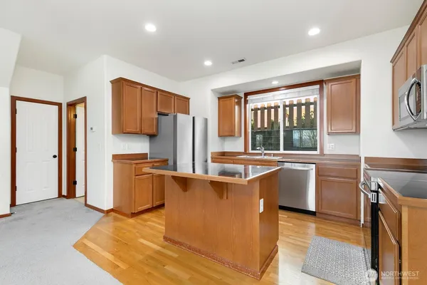 a kitchen with stainless steel appliances granite countertop a stove a sink a refrigerator and a microwave