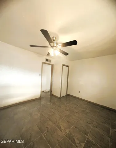 an empty room with a ceiling fan and carpet