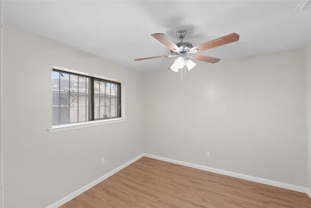 a view of an empty room with window and wooden floor