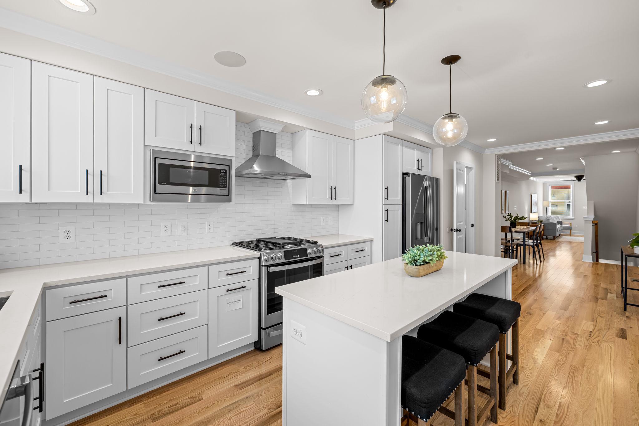 22 South Castle Street Baltimore, MD 21231 - Photo 15 of 32 a open kitchen with stainless steel appliances granite countertop a sink a stove a refrigerator and island with wooden floor