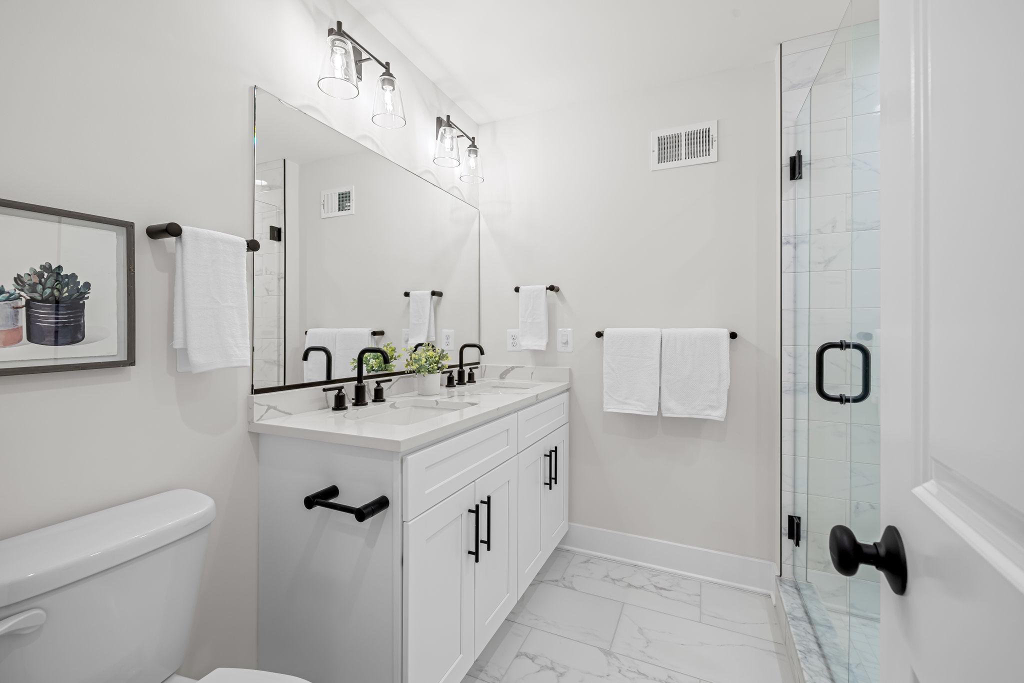 22 South Castle Street Baltimore, MD 21231 - Photo 23 of 32 a bathroom with a double vanity sink a toilet and a mirror
