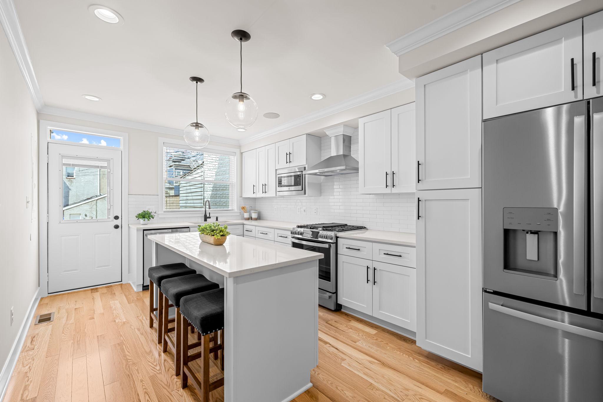 22 South Castle Street Baltimore, MD 21231 - Photo 10 of 32 a kitchen with stainless steel appliances granite countertop a refrigerator a sink dishwasher a stove and white countertops with wooden floor