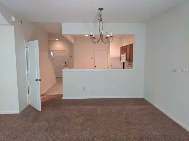 an empty room with chandelier fan and windows