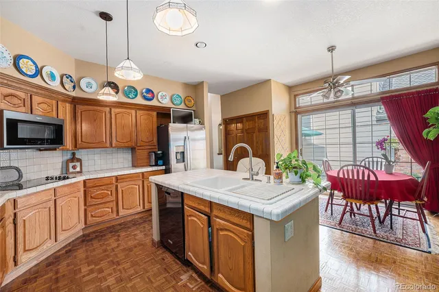 a kitchen with a refrigerator a stove a sink dishwasher with a dining table and chairs with wooden floor