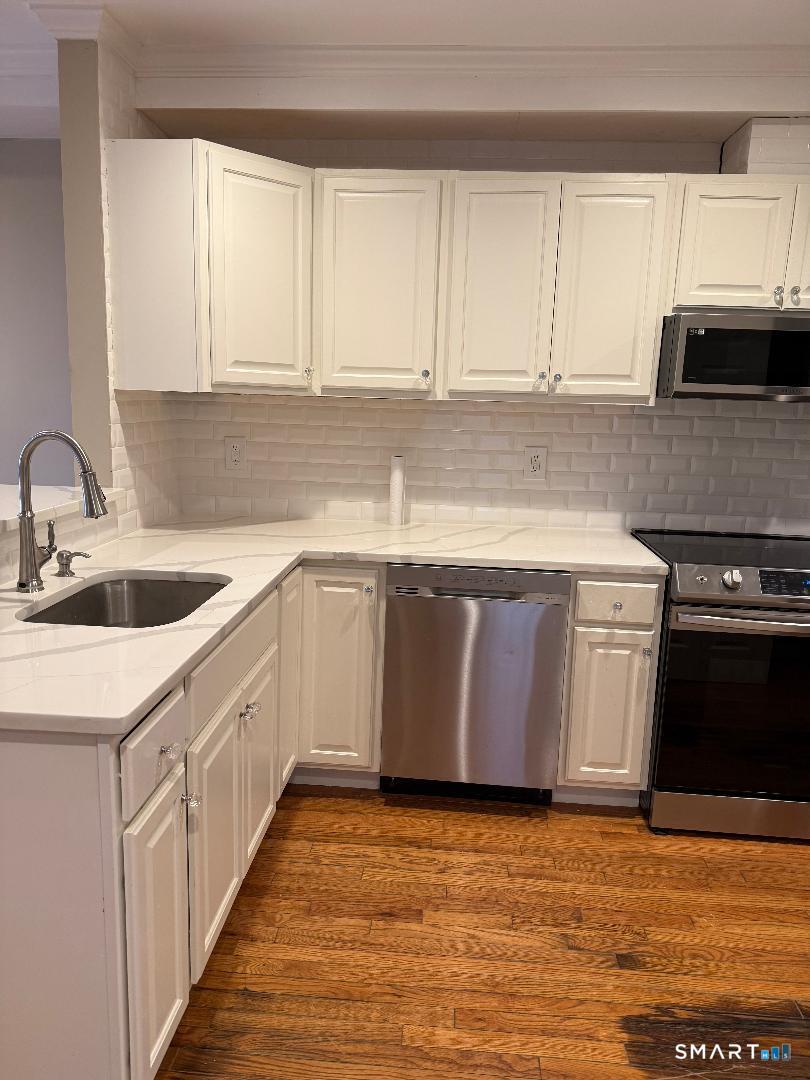 1 Beaver Brook Road, Unit 29 Danbury, CT 06810 - Photo 16 of 16 a kitchen with stainless steel appliances granite countertop a sink stove and white cabinets with wooden floor