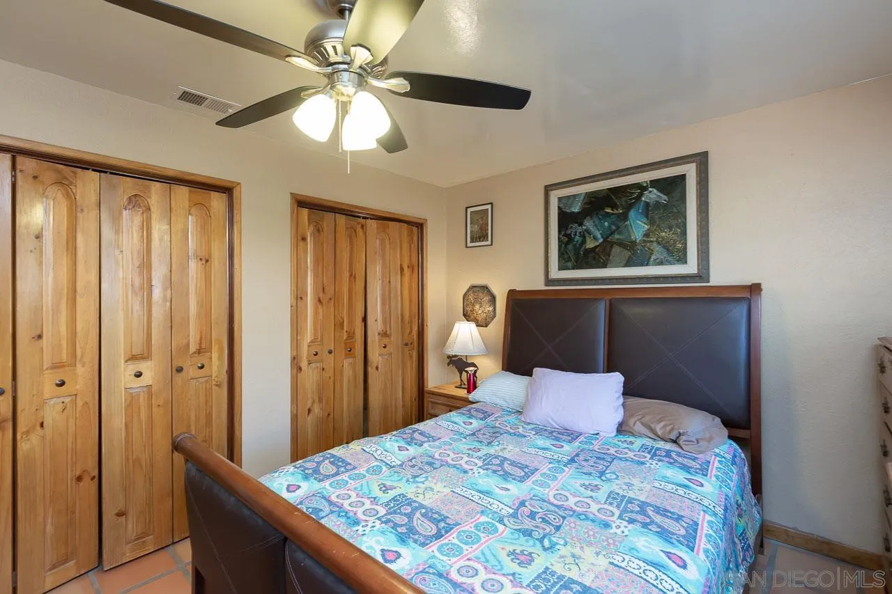 2029 Willow Glen Road Fallbrook, CA 92028 - Photo 16 of 46 a bedroom with a bed and a chandelier