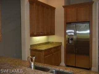 5738 Mango Circle, Unit 5738 Naples, FL 34110 - Photo 4 of 8 a kitchen with a refrigerator and cabinets