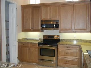 5738 Mango Circle, Unit 5738 Naples, FL 34110 - Photo 5 of 8 a kitchen with granite countertop white cabinets and stainless steel appliances