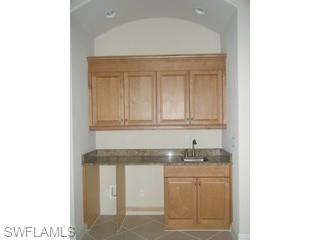 5738 Mango Circle, Unit 5738 Naples, FL 34110 - Photo 6 of 8 a bathroom with granite countertop white cabinets and a sink