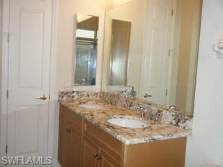 5738 Mango Circle, Unit 5738 Naples, FL 34110 - Photo 8 of 8 a bathroom with a granite countertop sink and a mirror
