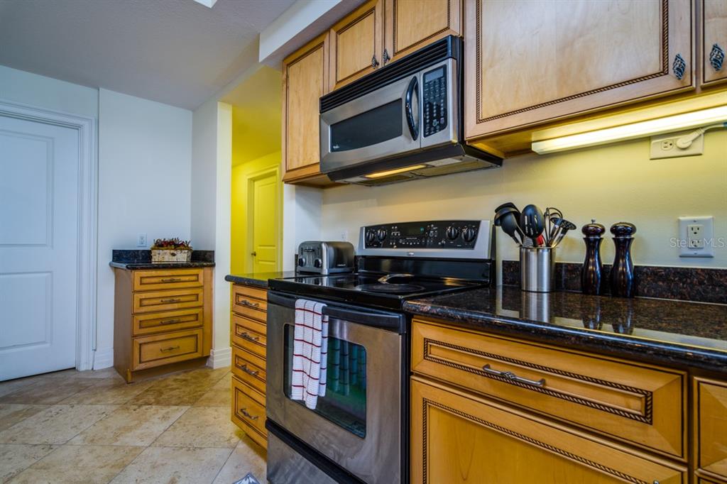 1350 Gulf Boulevard, Unit 901 Clearwater Beach, FL 33767 - Photo 21 of 63 a kitchen with stainless steel appliances granite countertop a stove and a microwave