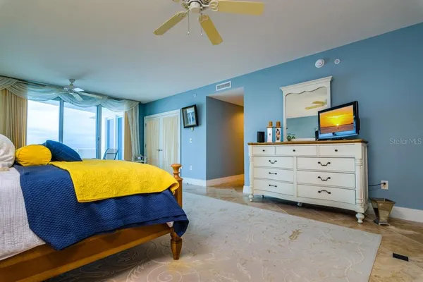 a bedroom with a bed chair and wall painting on the wall