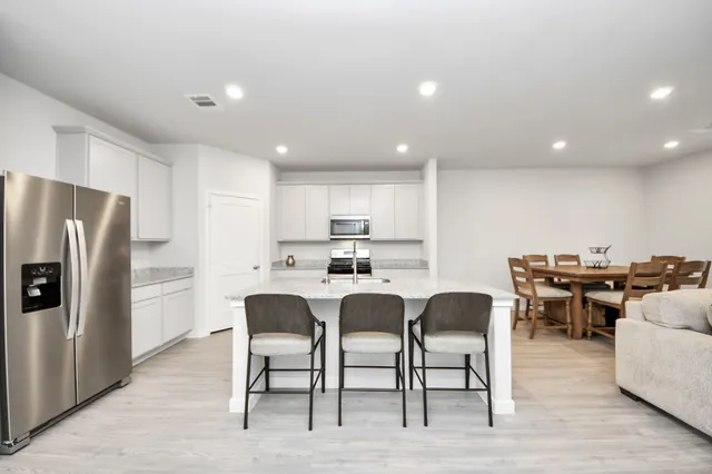 a kitchen with a dining table chairs refrigerator and stove