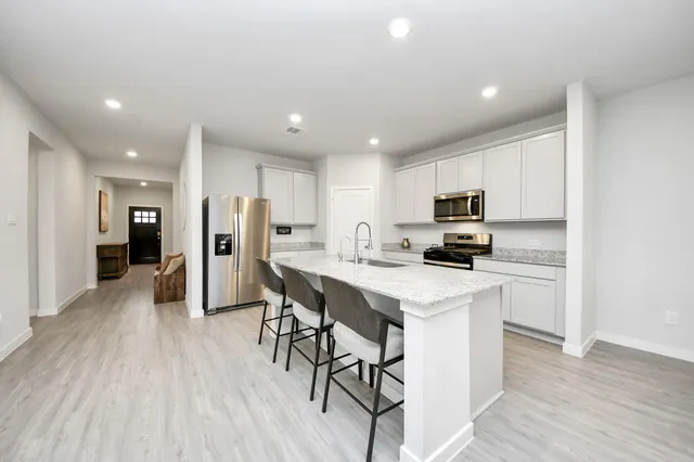 a kitchen with stainless steel appliances a refrigerator a stove top oven and a center island with wooden floor