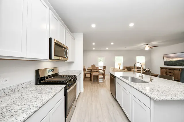 a kitchen with stainless steel appliances granite countertop sink stove microwave and cabinets