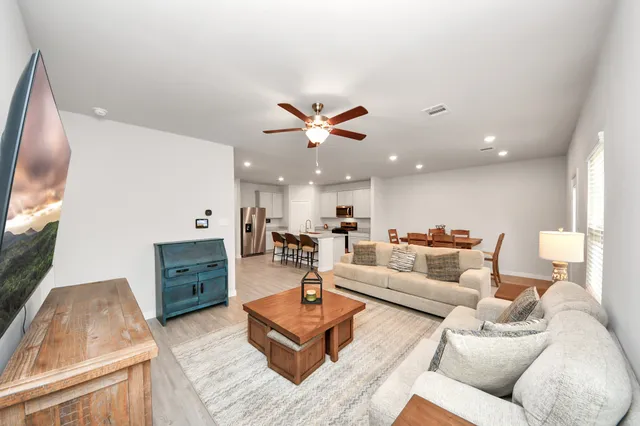 a living room with furniture kitchen view and a flat screen tv