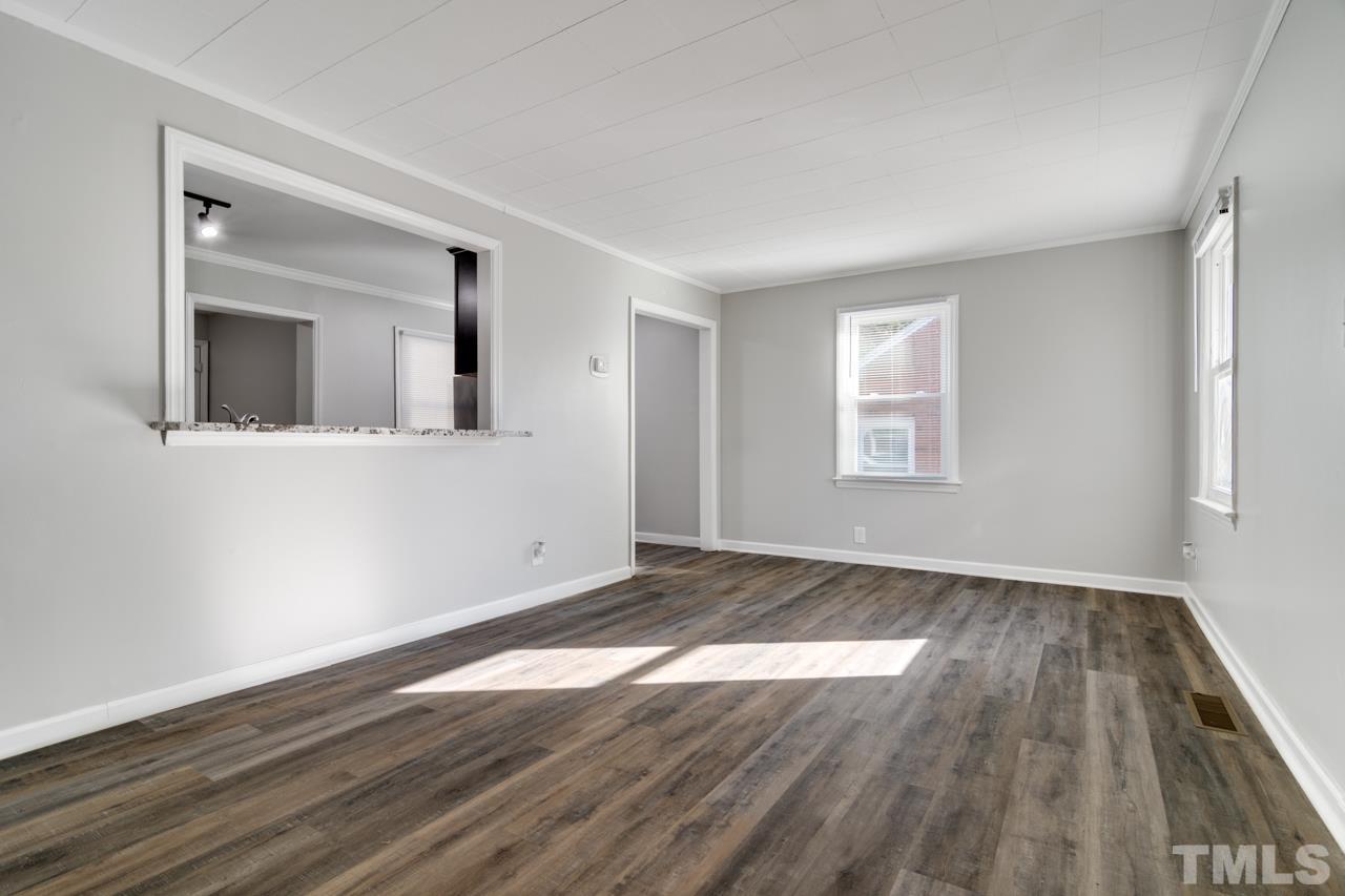 213 Angier Avenue Raleigh, NC 27610 - Photo 9 of 38 a view of an empty room with wooden floor and a window