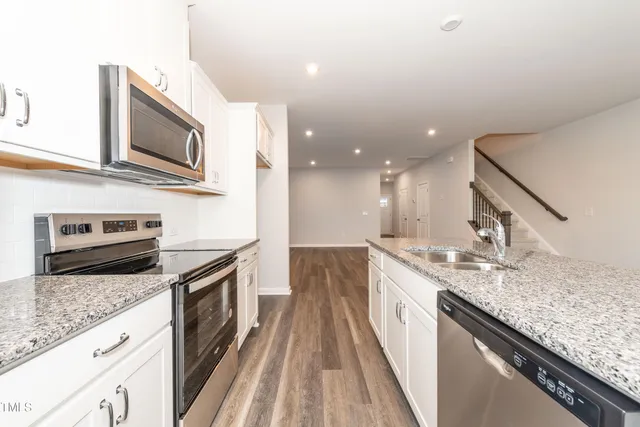 a large kitchen with granite countertop a sink and a stove