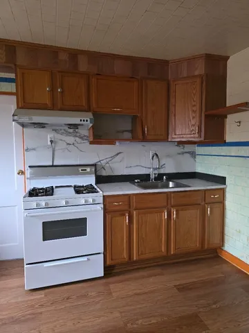 a kitchen with granite countertop wooden cabinets and a stove top oven