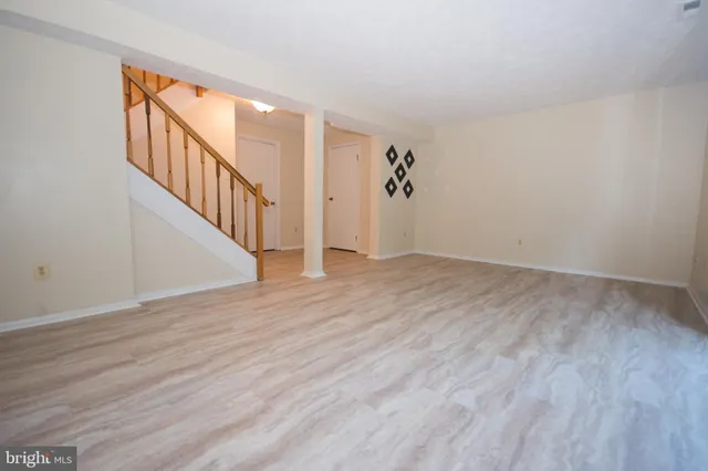 a view of an empty room with wooden floor and stairs