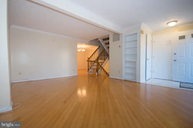 a view of empty room with wooden floor and stairs