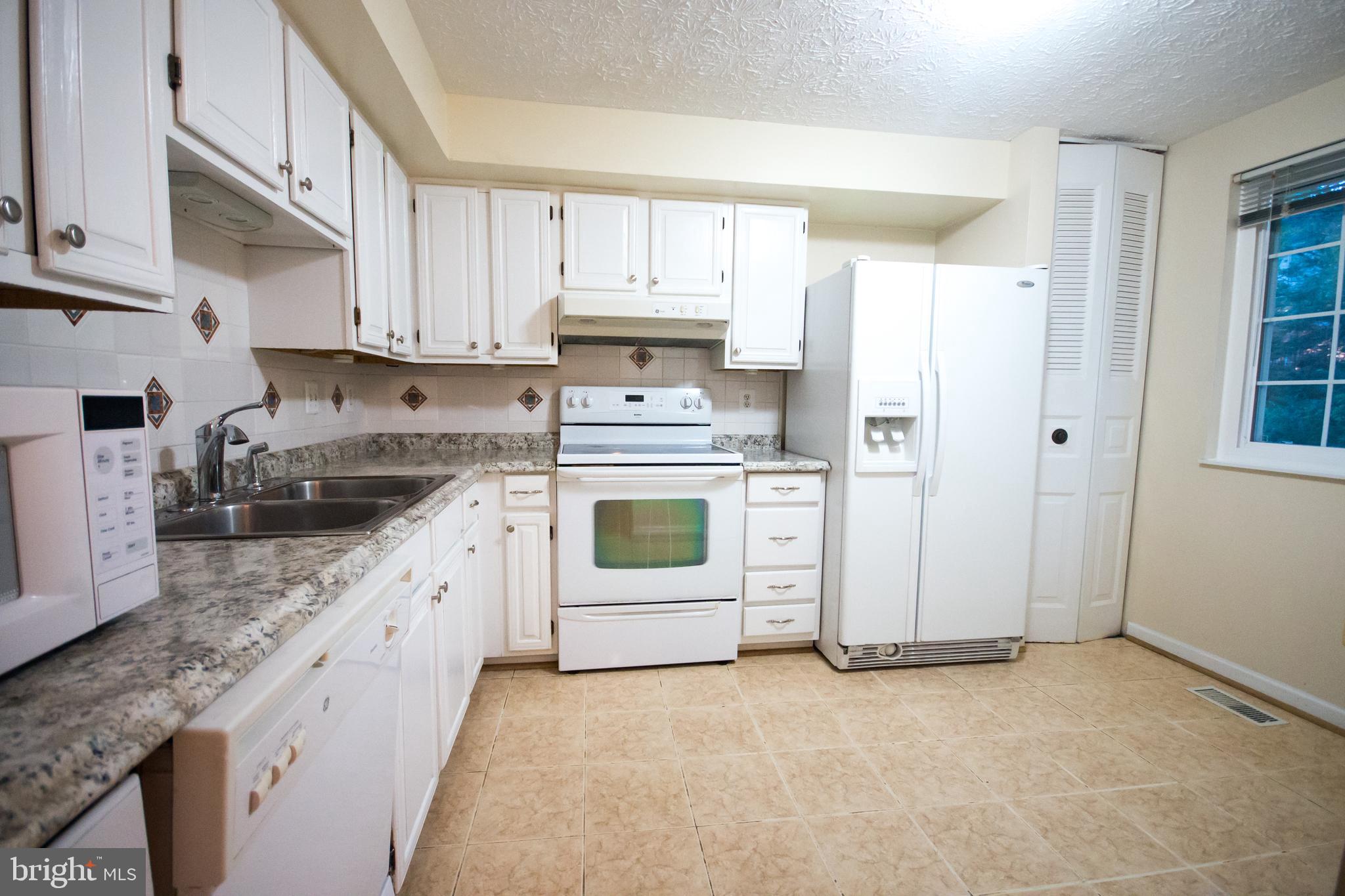 7993 Tyson Oaks Circle Vienna, VA 22182 - Photo 6 of 25 a kitchen with white cabinets and white appliances