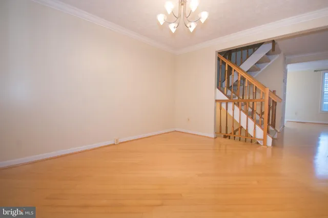 a view of an empty room with wooden floor and stairs
