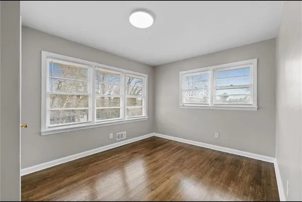an empty room with wooden floor and windows