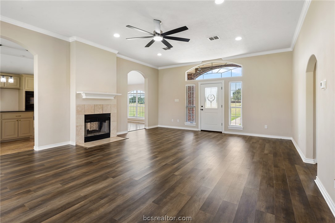 6100 Whitetail Lane Bryan, TX 77808 - Photo 8 of 37 an empty room with wooden floor a ceiling fan a fireplace and windows