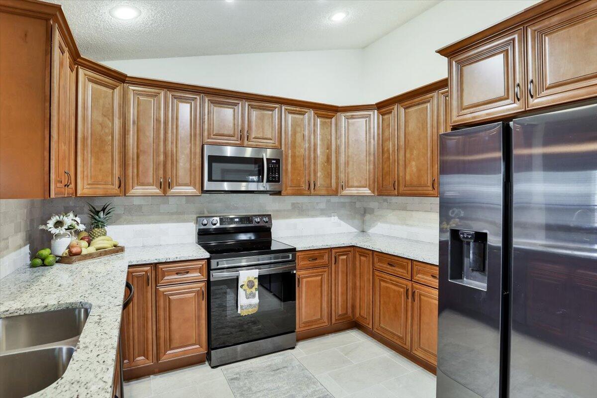 19681 Southeast County Line Road Tequesta, FL 33469 - Photo 12 of 45 a kitchen with stainless steel appliances granite countertop a refrigerator stove and sink