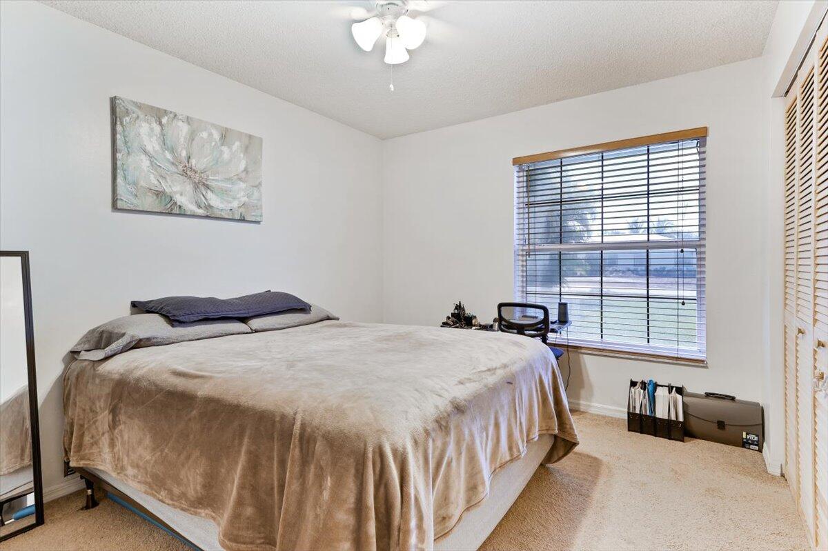 19681 Southeast County Line Road Tequesta, FL 33469 - Photo 20 of 45 a bedroom with a bed a couch and a large window