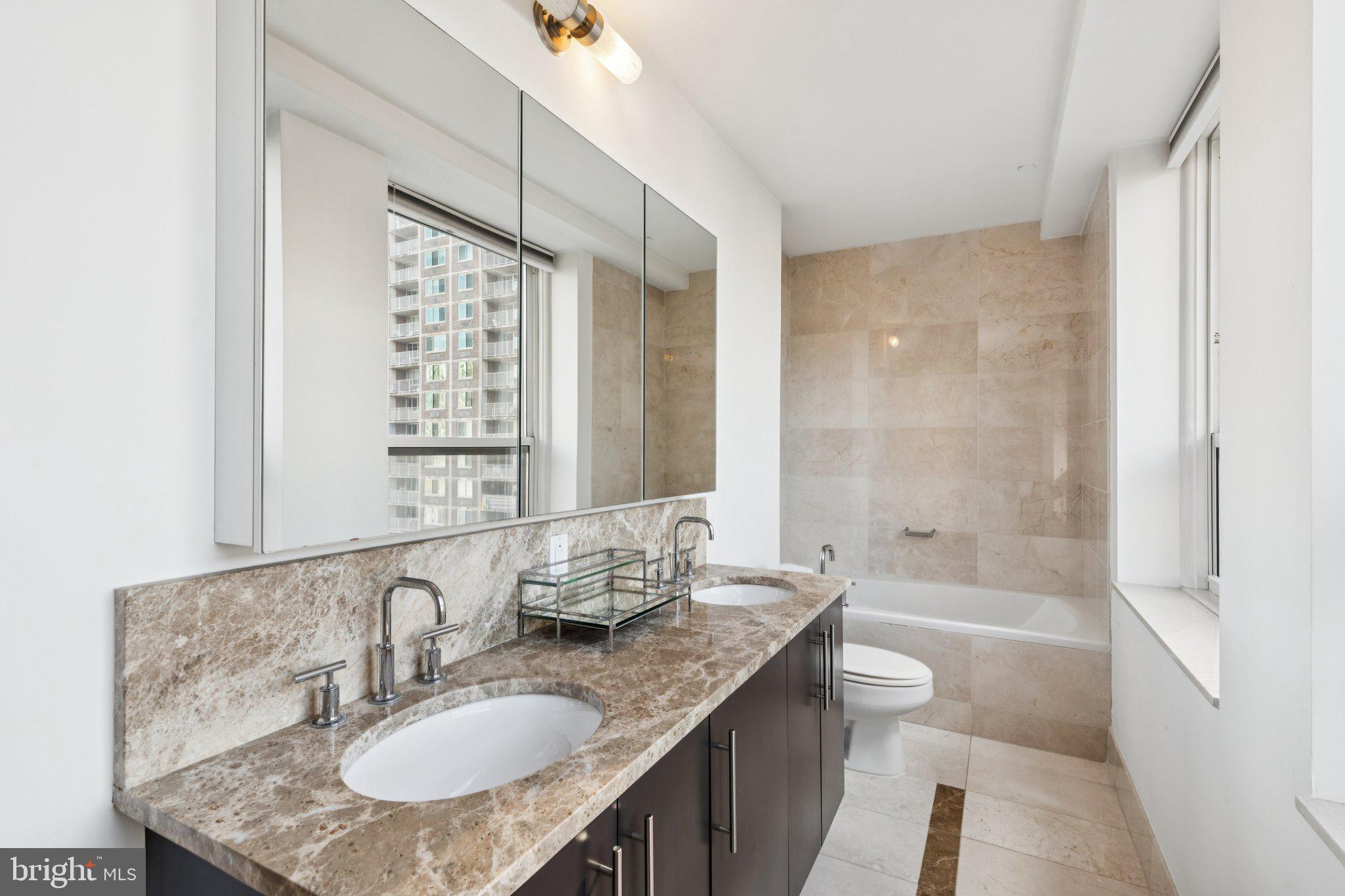 1425 Locust Street, Unit 21A Philadelphia, PA 19102 - Photo 4 of 8 a bathroom with a granite countertop sink a toilet a mirror and shower